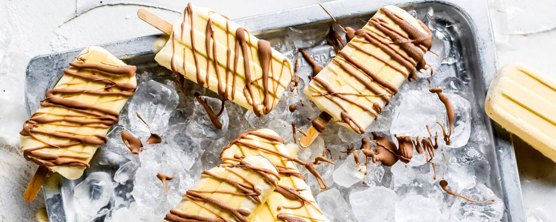 Paletas heladas de vainilla cubiertas con chocolate Kinder Maxi sobre hielo