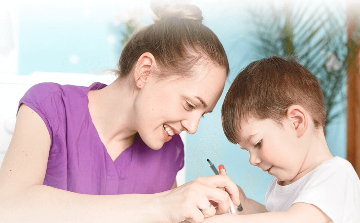 Primer plano de los rostros de una mujer y un niño que dibujan sonriendo.