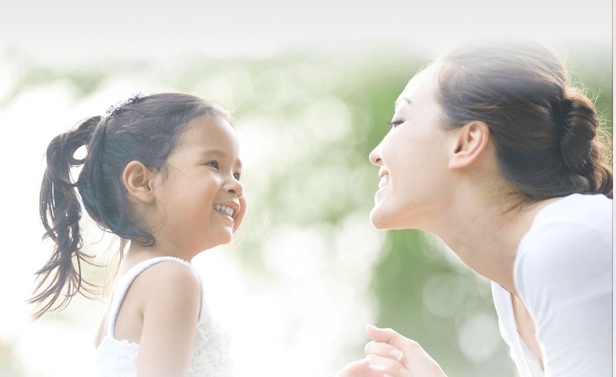 Las caras de mamá y niña frente a frente sonriendo