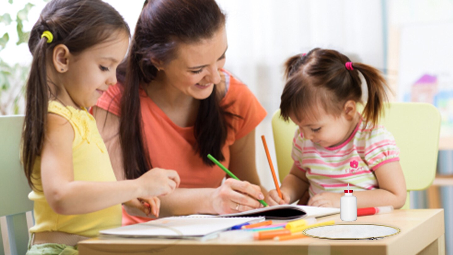 Mamá con dos niñas pequeñas realizando dibujos conn lápices de colores sobre una mesa