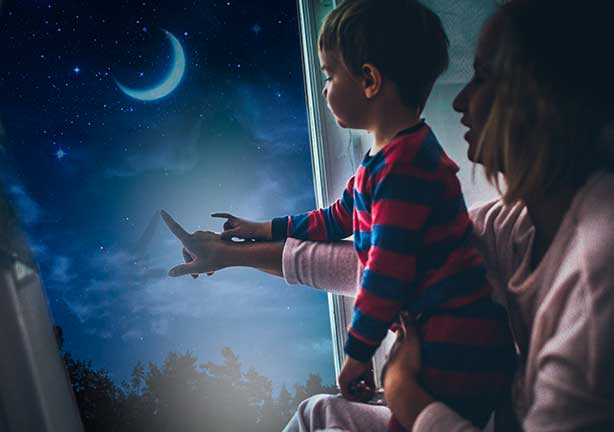 Mamá y niño pequeño mirando el cielo nocturno a través de la ventana.