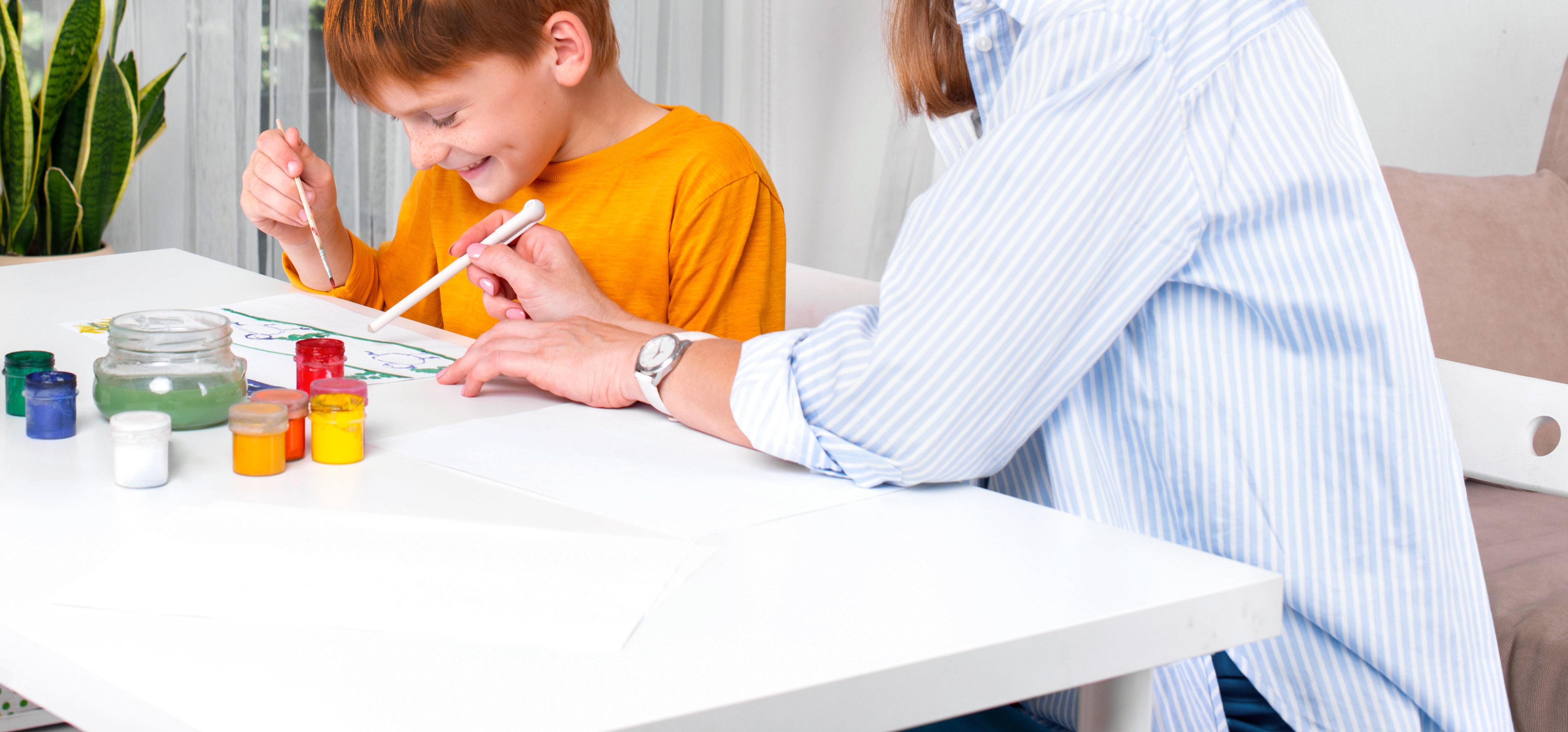 Mamá y niño divertidos y atentos a un papel sobre la mesa.