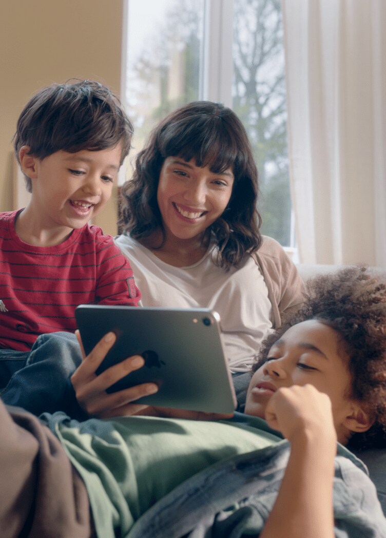 Woman with two young boys playing with an iPad